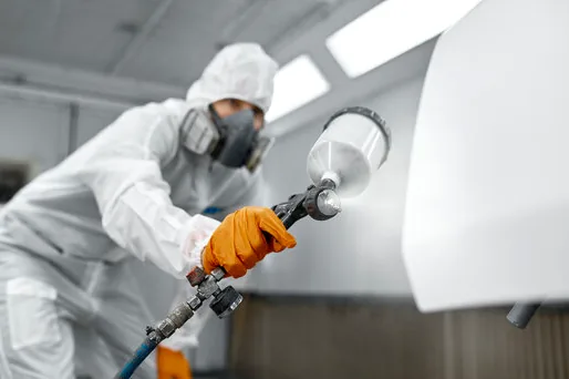 Painter in a protective suit spraying a smooth finish