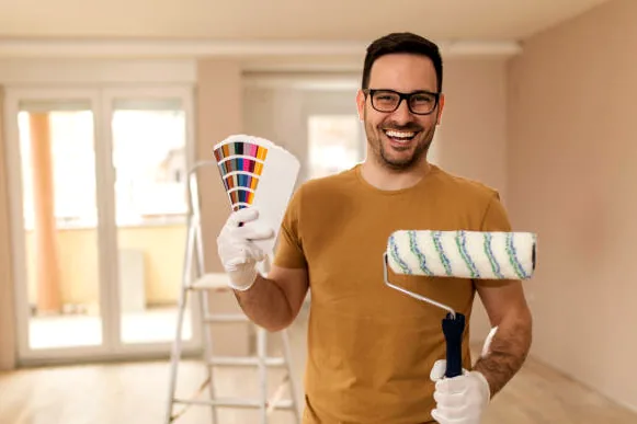 Painter smiling and holding a fan deck of paint colors and a roller