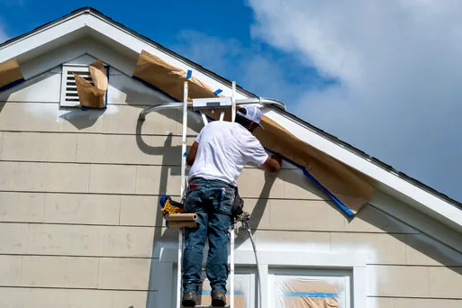 Painter on a ladder at a gable with lap siding
